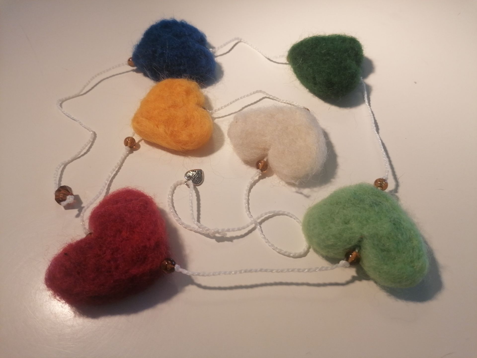 Hartenslinger van vilt in de kleuren rood, oranje, wit, groen en blauw, met kralen.