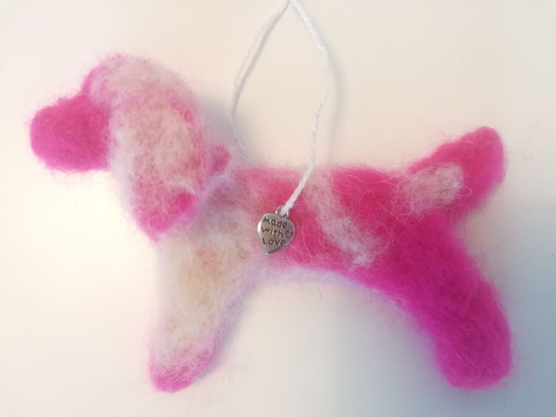 Roze en wit vilten ornament met zilveren hartbedel en ophangkoordje.