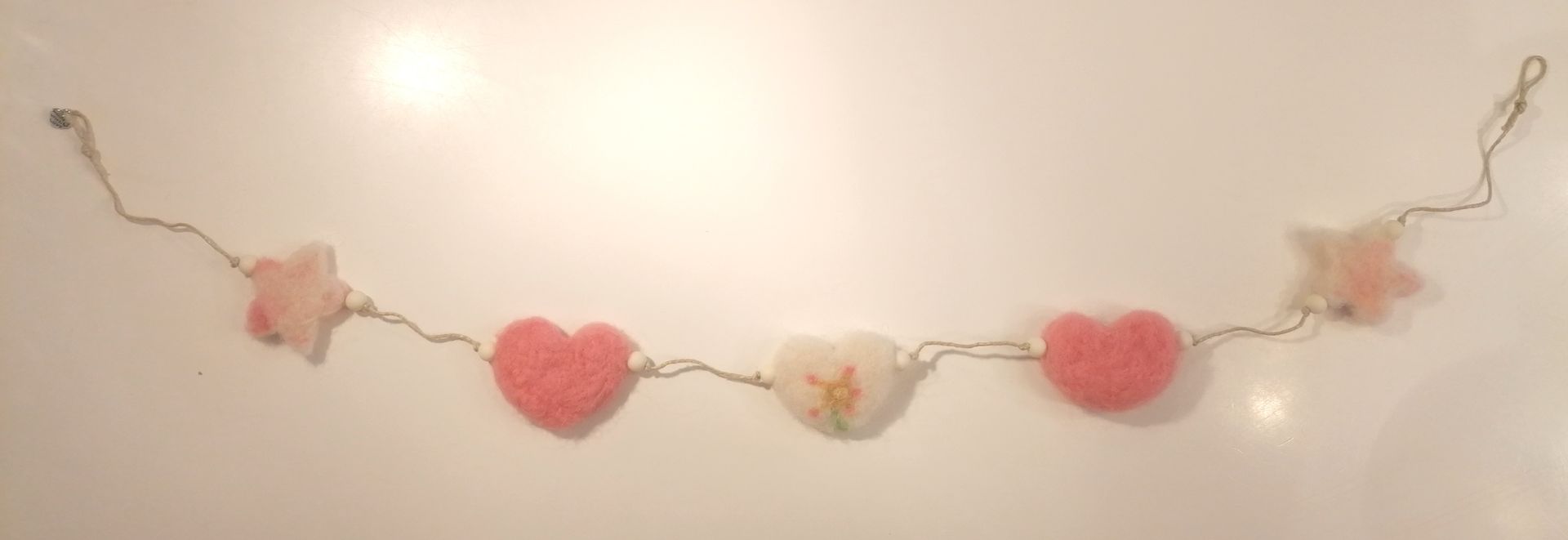 Een slinger van roze harten en sterren geregen op draad.