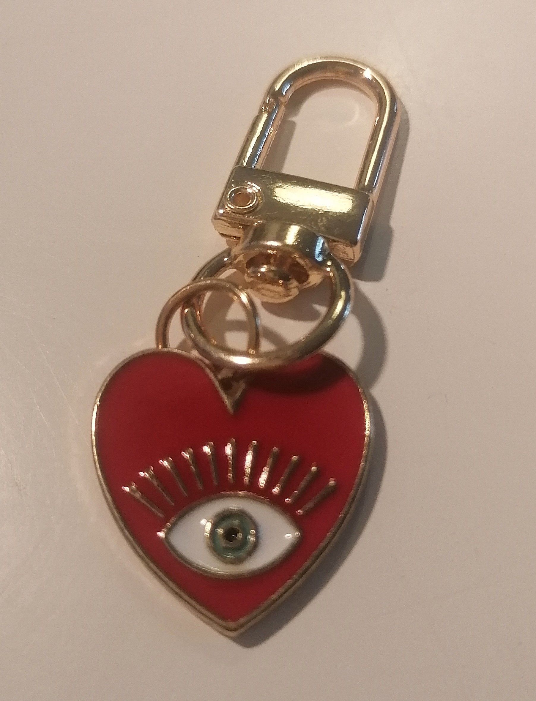 Rozenkwartskristal met een smudgeveer, wollen hartje en decoratieve sleutelhanger.