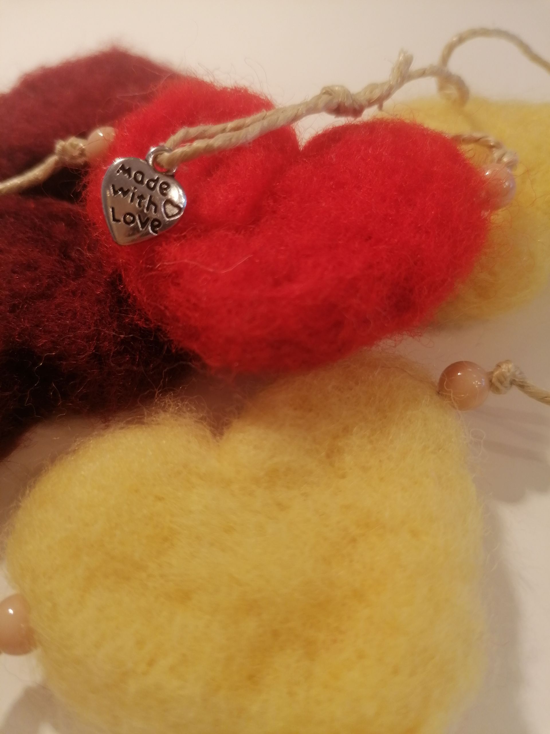 Hartenslinger van vilt in de kleuren rood, geel en kastanjebruin, met het opschrift