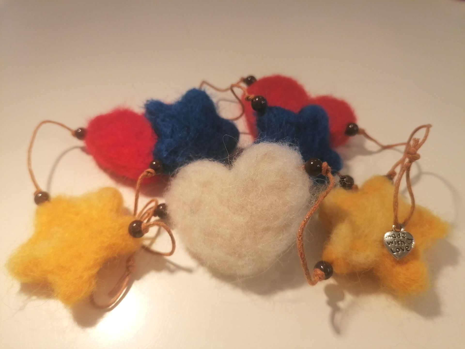 Een decoratieve kaart met een waxinelichtje, wol ornament in de vorm van hart met boodschap,een ster van wol en een vlinder.