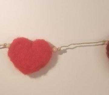 Rode vilten hartenslinger met parelkralen.