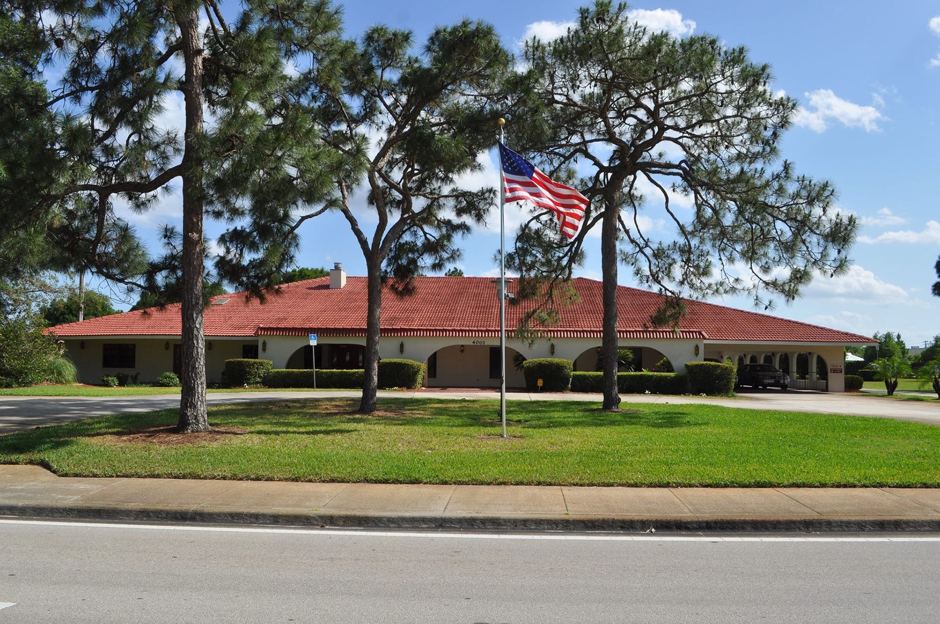 Building with red tile roof, arched entryways, and American flag.