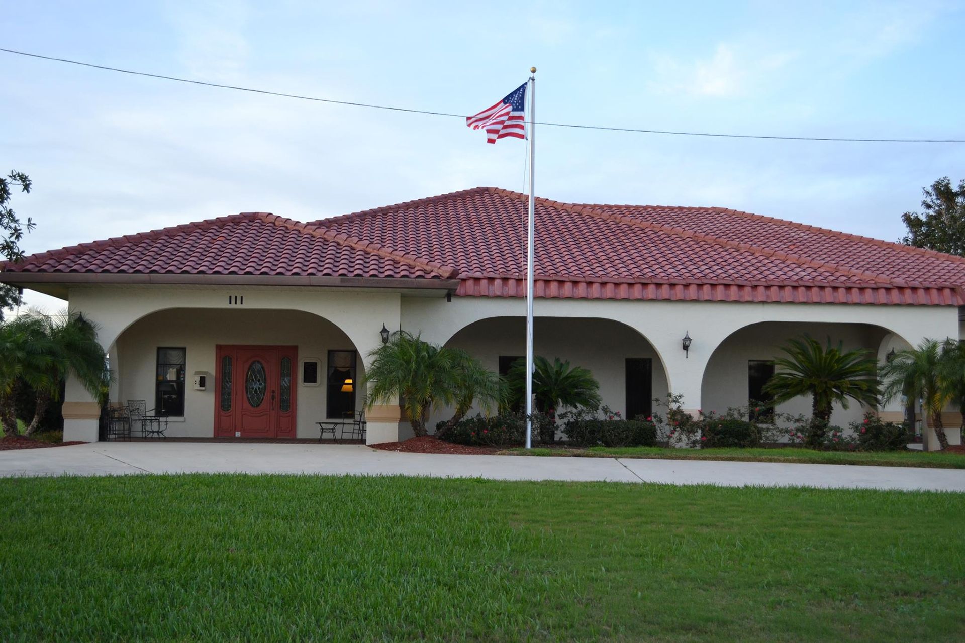Building with red tile roof, arched entryways, and American flag.