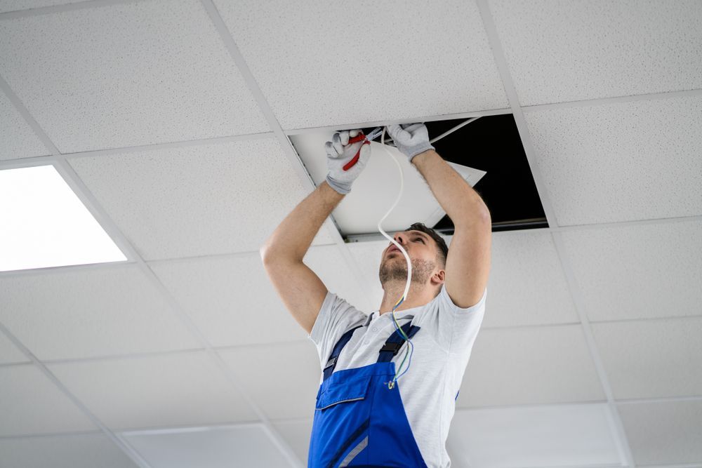 Worker in Blue Overalls Repairing Ceiling Lights — Local Light Electrical in Suffolk Park, NSW