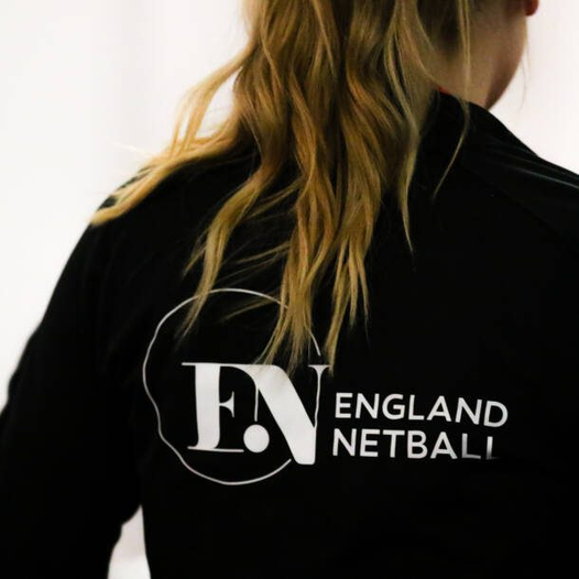 A woman is wearing a black shirt that says england netball