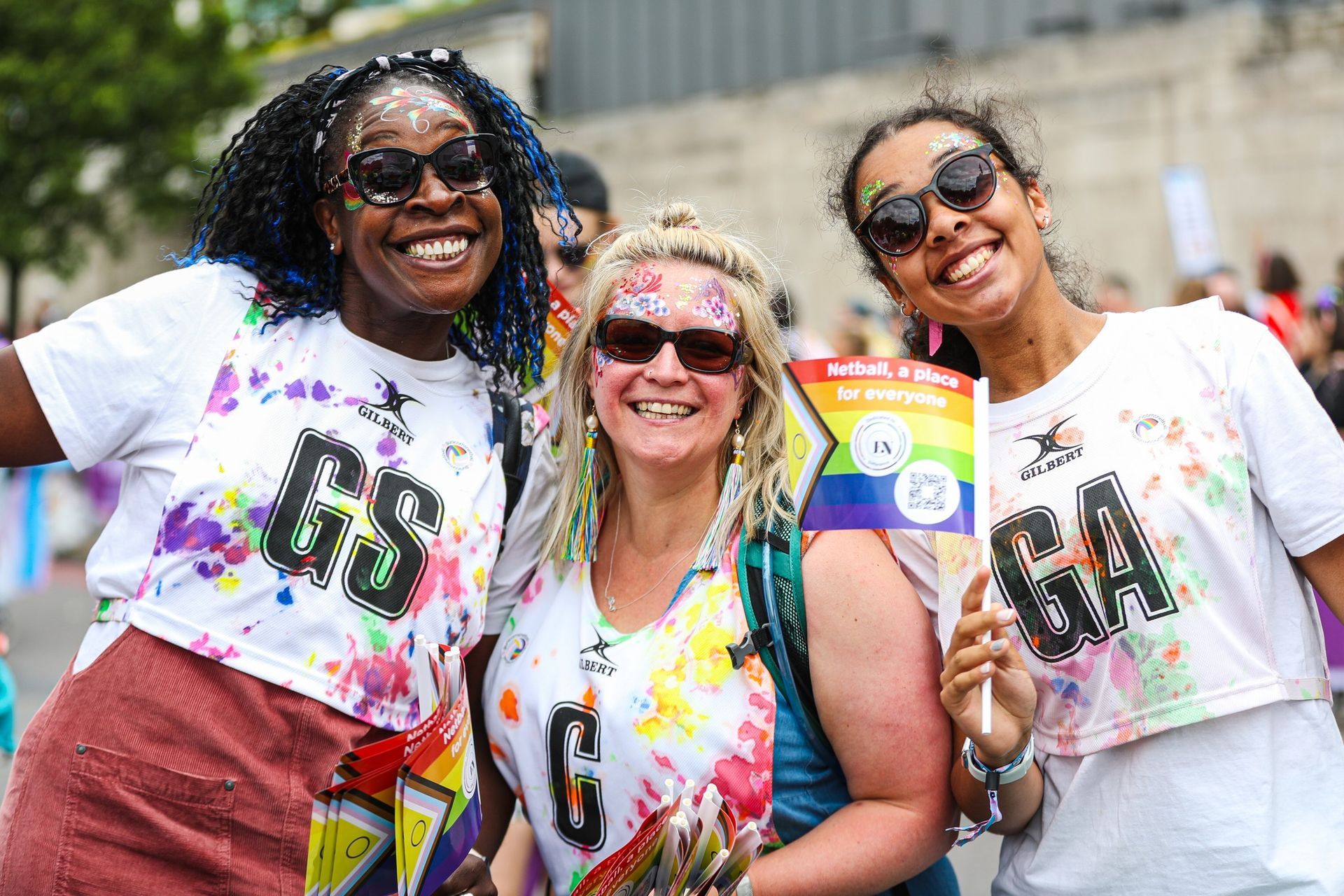 Three women are posing for a picture at a pride parade.