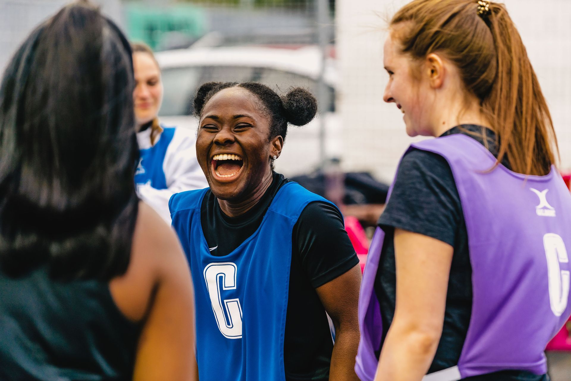 A group of young women are standing in a circle laughing.
