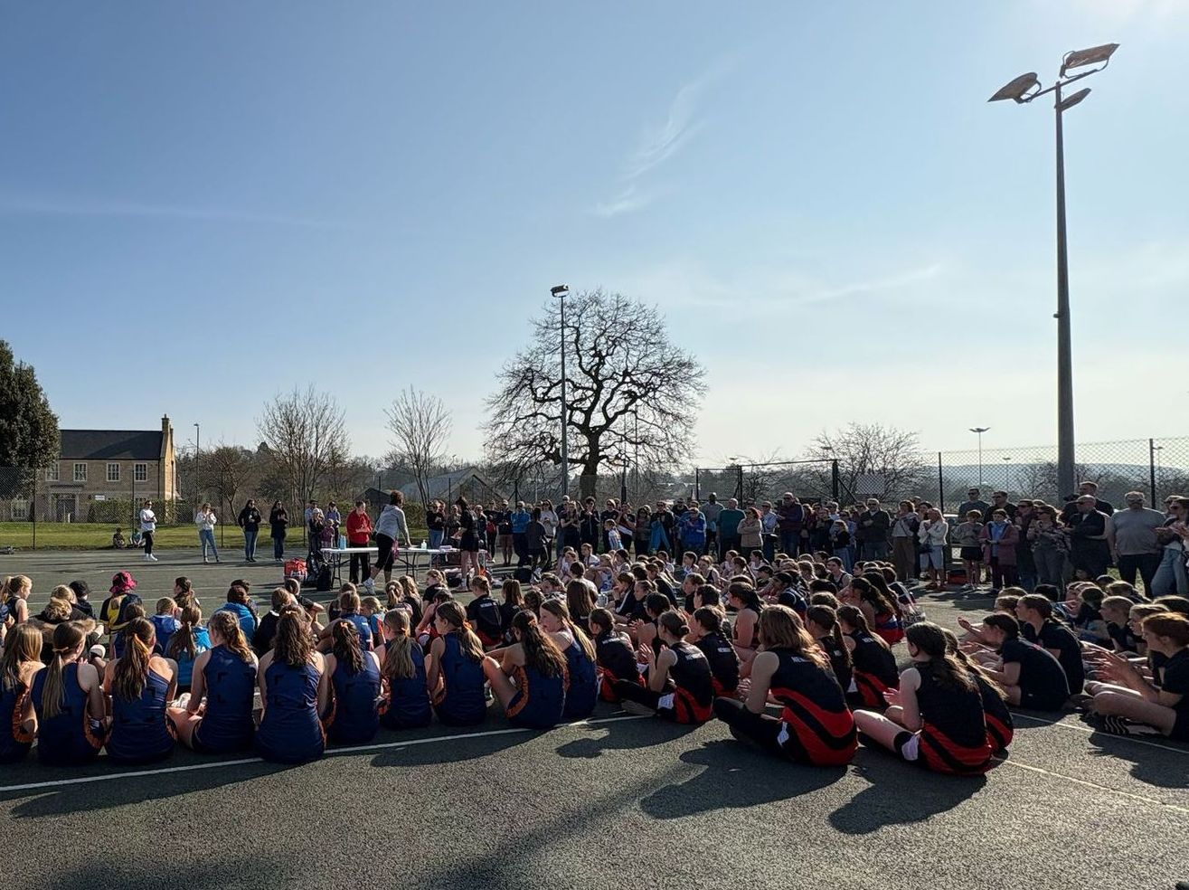 A woman in a red jacket is standing in front of a group of people.