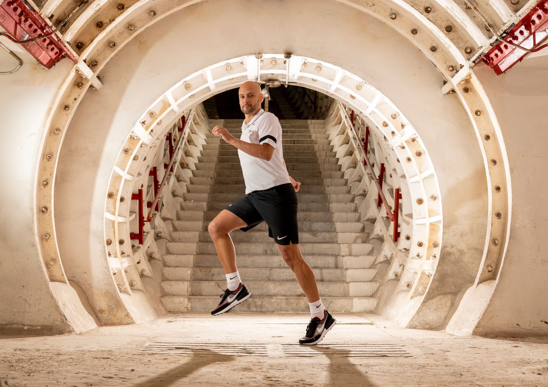 A man is running through a tunnel with stairs.