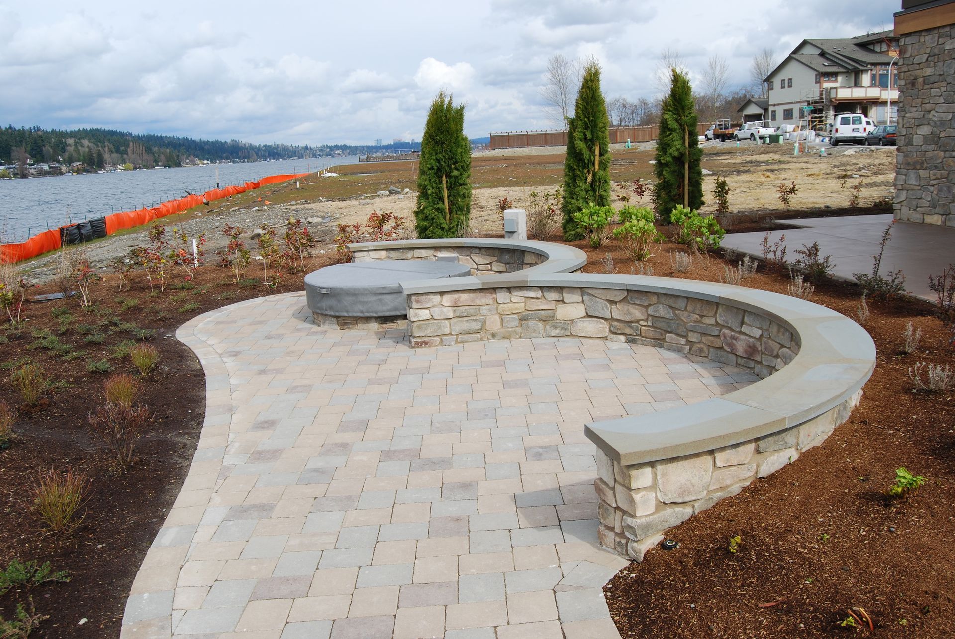 Curved stone walkway with built-in seating overlooking a waterfront and landscaped shrubs