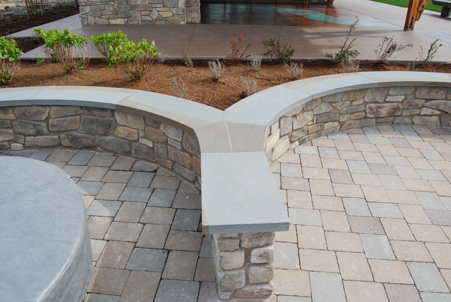Stone patio with curved built-in benches and low retaining walls around a landscaped courtyard.