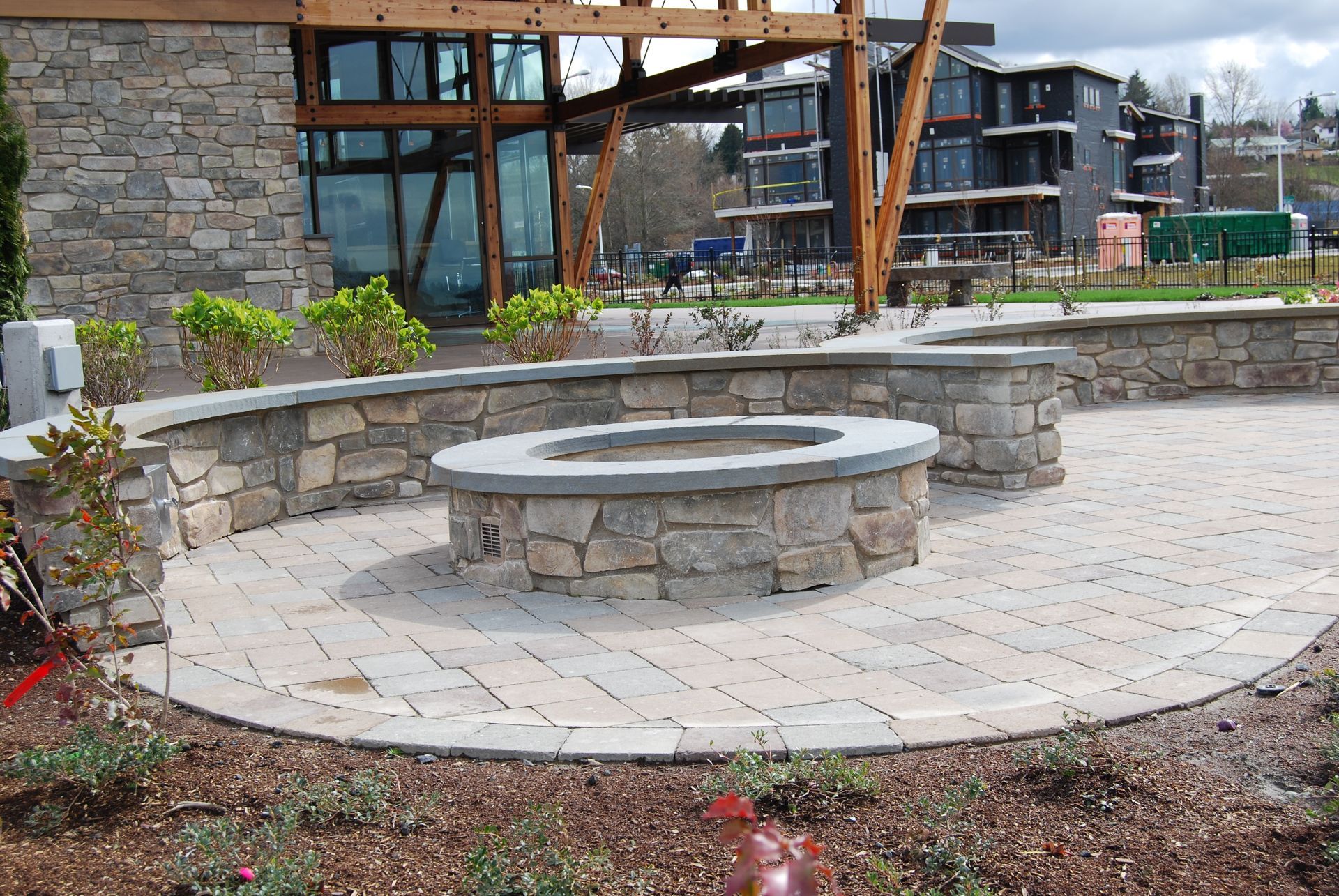 Stone courtyard with circular bench and low retaining wall beside a modern building