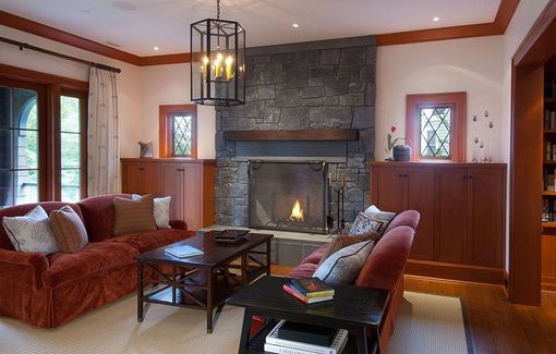 Cozy living room with a stone fireplace, red sofas, wood trim, and a hanging lantern light.