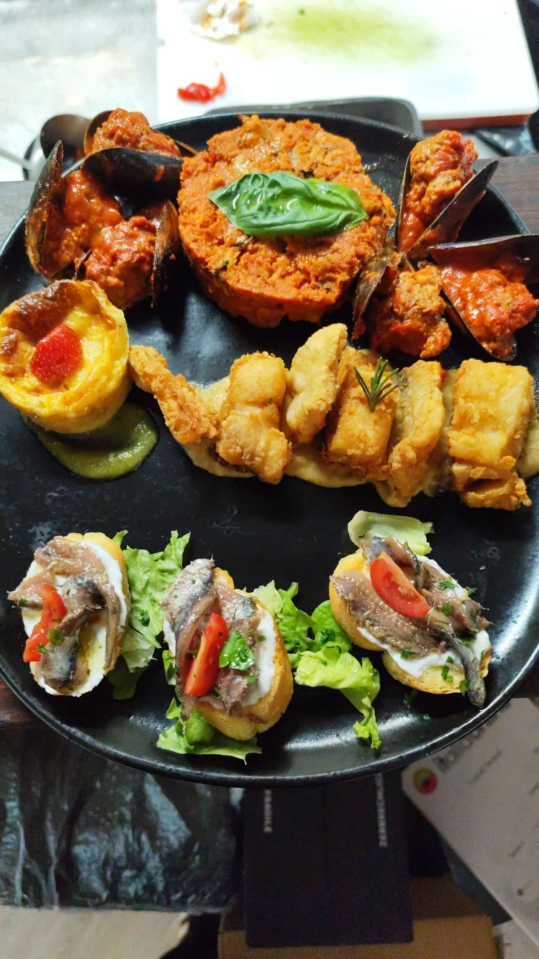 Piatto di antipasti di mare: cozze, frittura di pesce, riso al pomodoro, bruschetta alle acciughe.