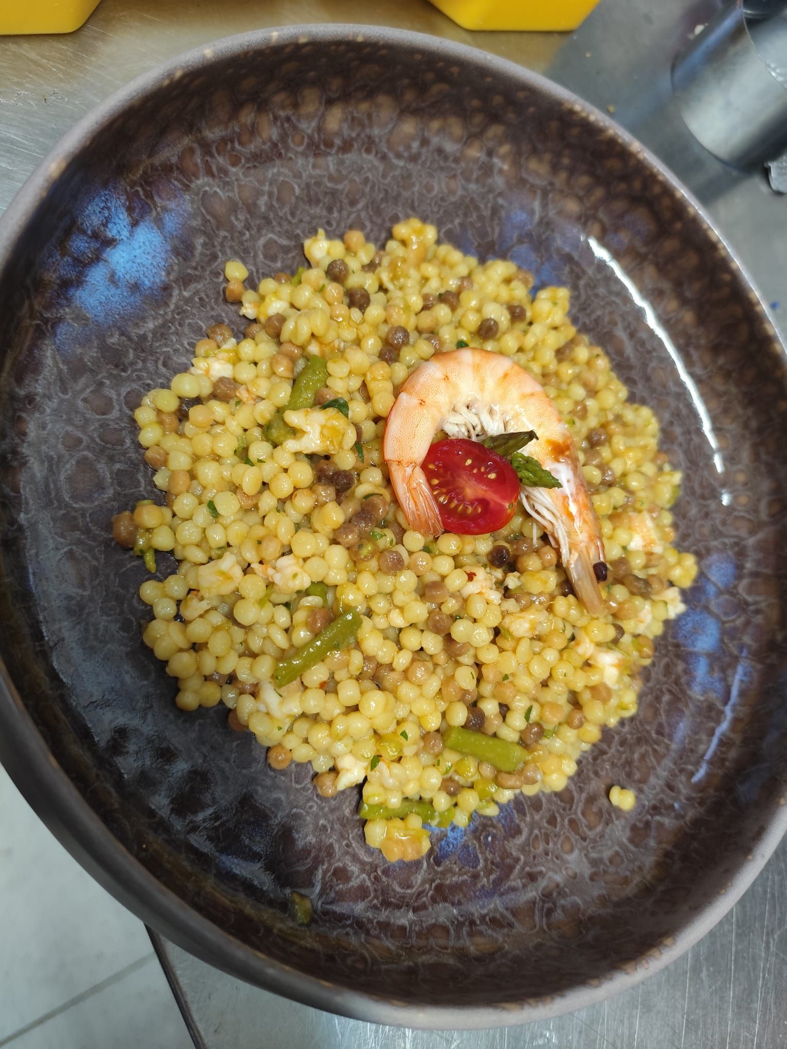 Un piatto di couscous con gamberi, pomodori e verdure.