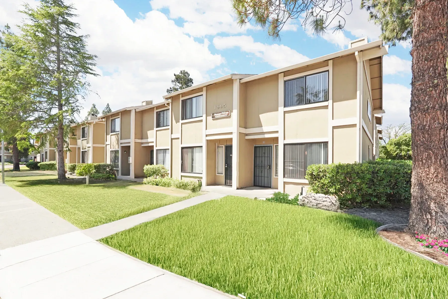Exterior view of apartment buildings with manicured lawns and trees.
