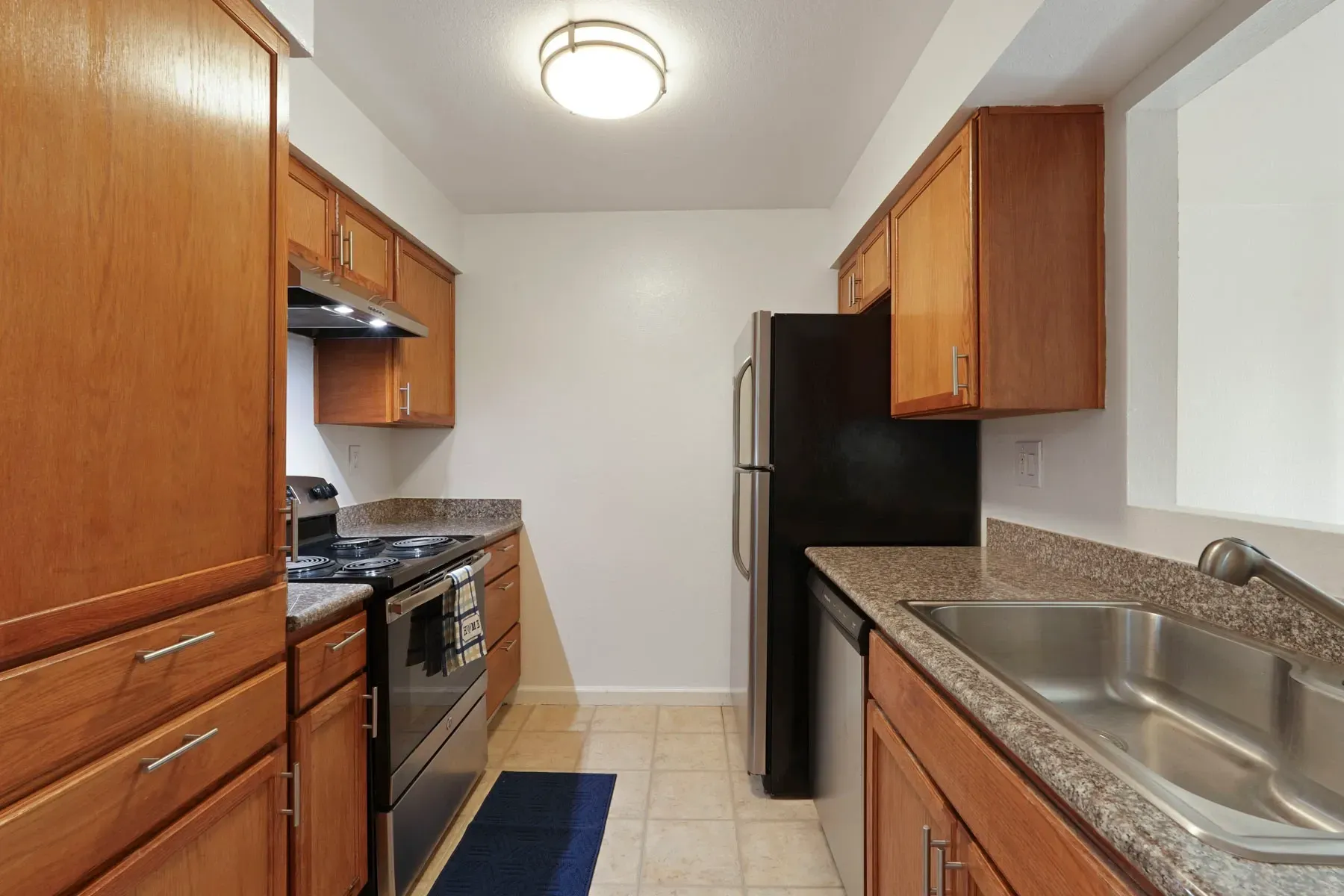 Kitchen with wood cabinets, granite countertops, stainless steel appliances, and tile flooring.