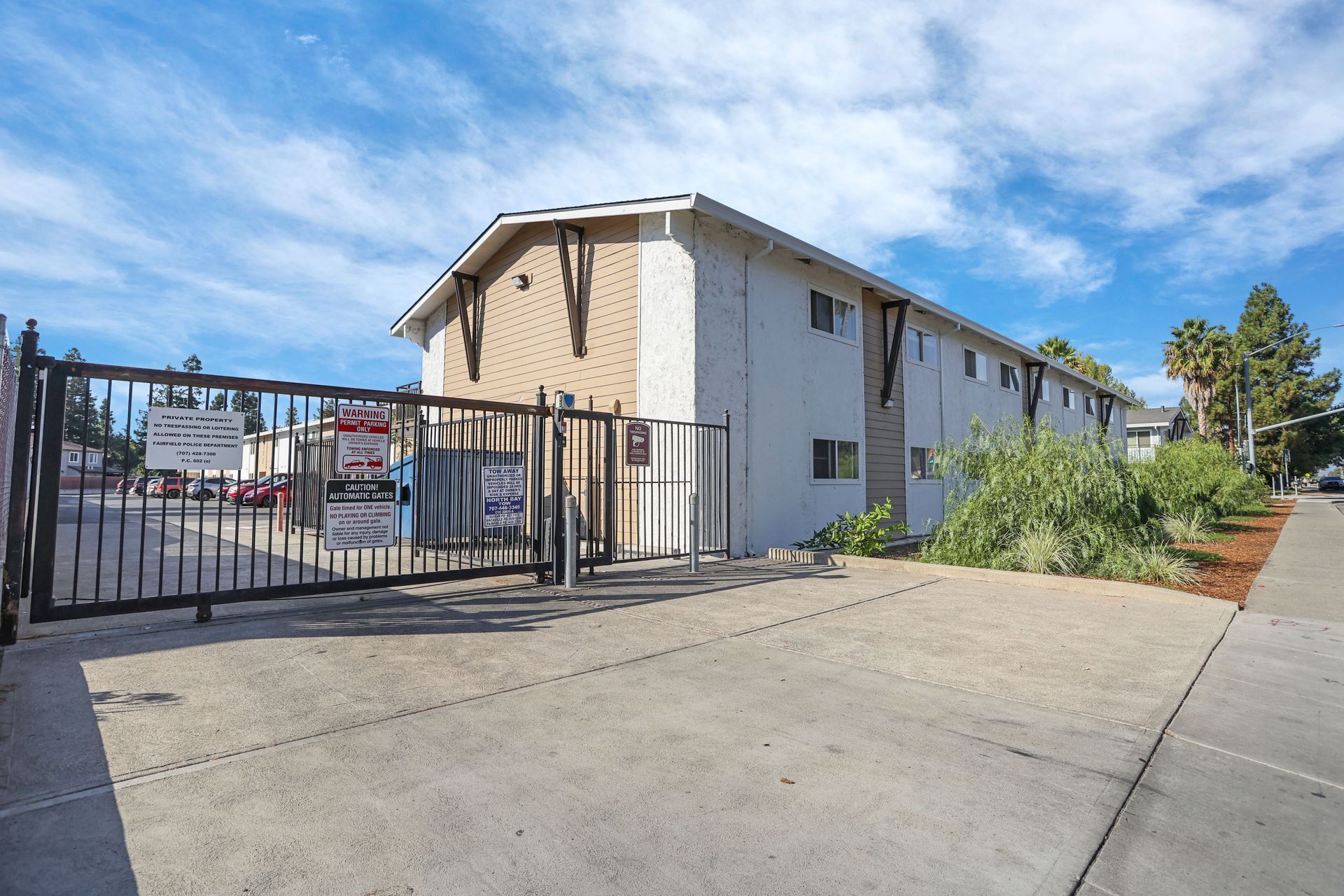 Gated apartment building with concrete driveway and blue sky