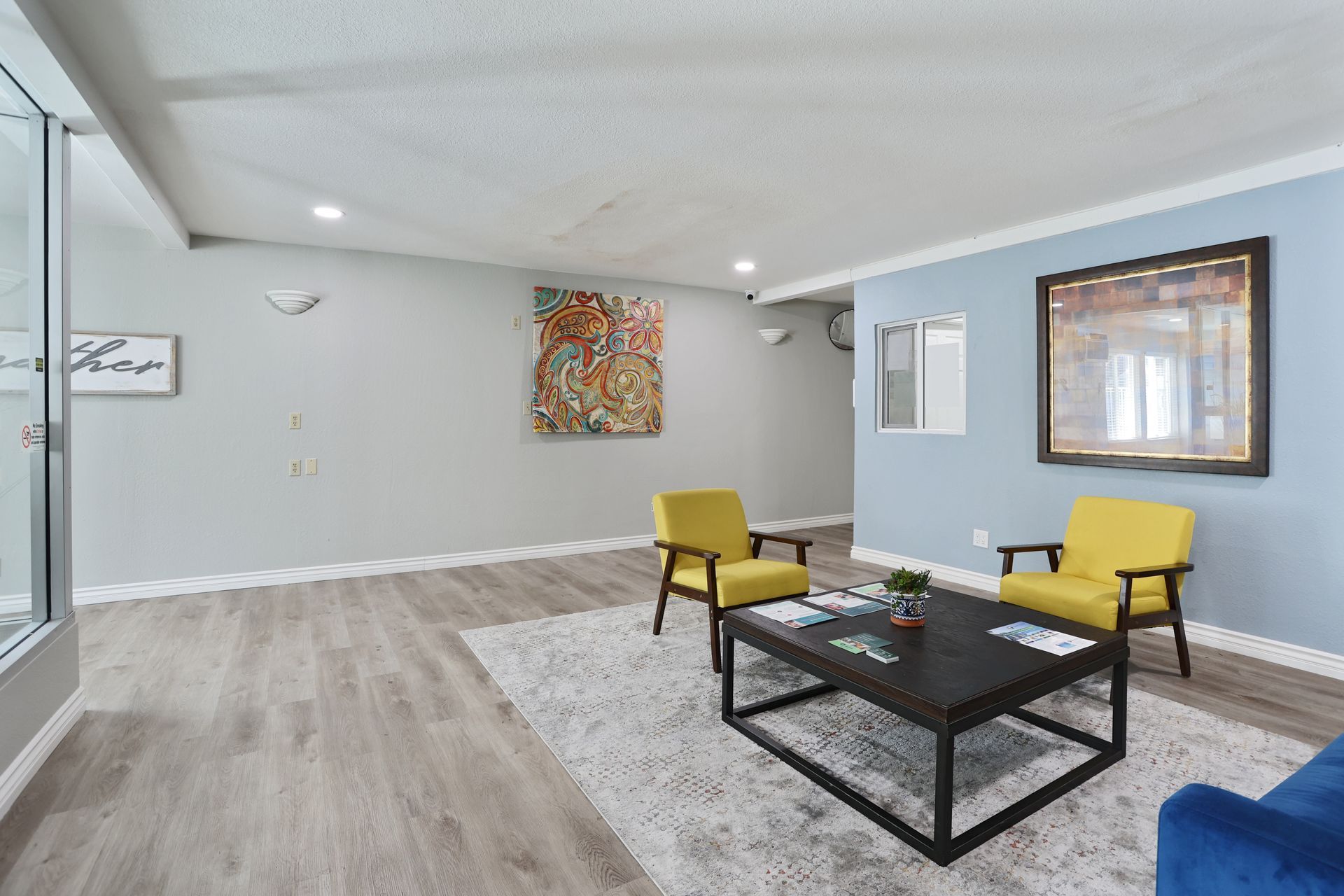 Modern waiting room with yellow chairs, black coffee table, wall art, and gray walls