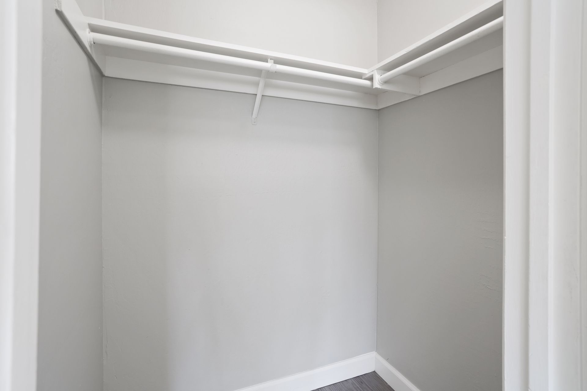 Empty walk-in closet with white walls and hanging rods