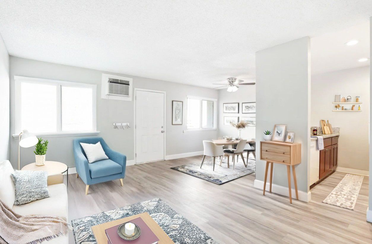 Bright modern living room with blue chair, dining area, and light wood floors