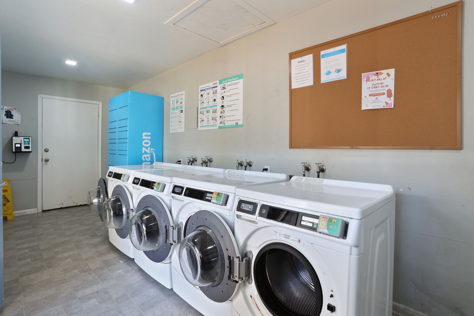 Laundry room with four front-loading washers, a blue machine, and bulletin boards on the wall