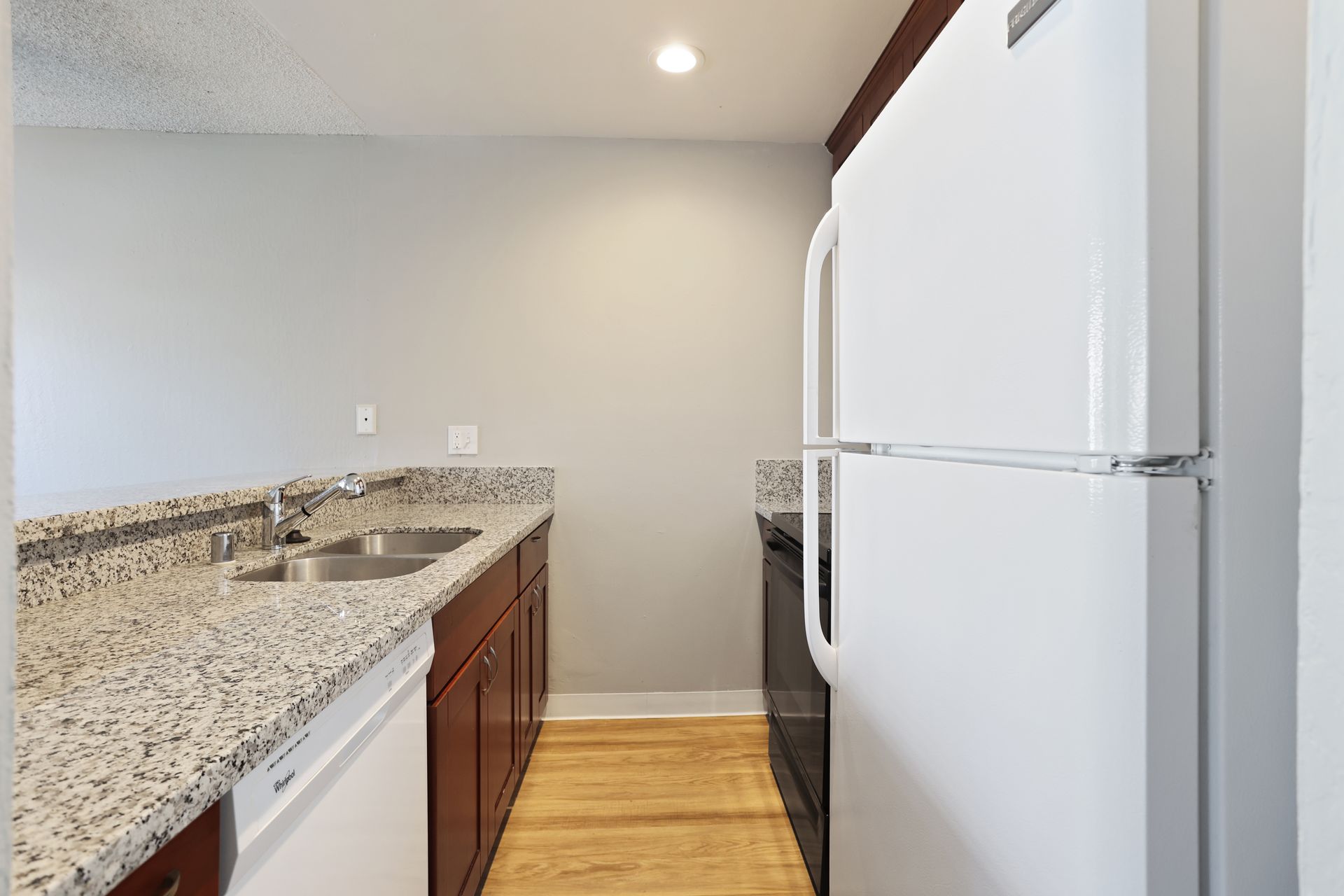 Modern kitchen with granite counters, wooden cabinets, and a white refrigerator