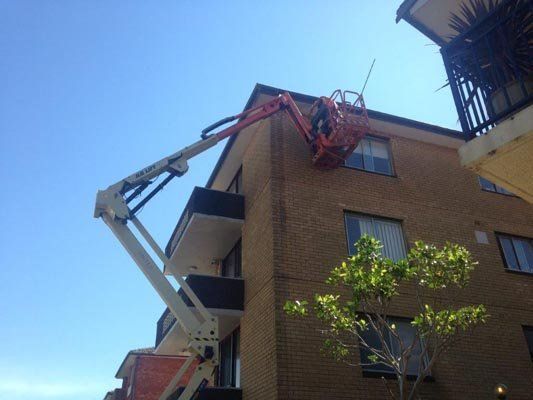 A crane is working on the roof of a building