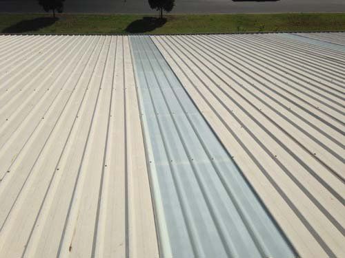 The roof of a building is being painted white and gray.