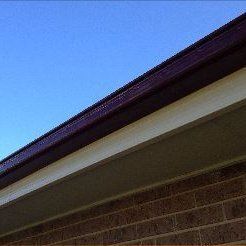 A close up of the roof of a brick house with a blue sky in the background.