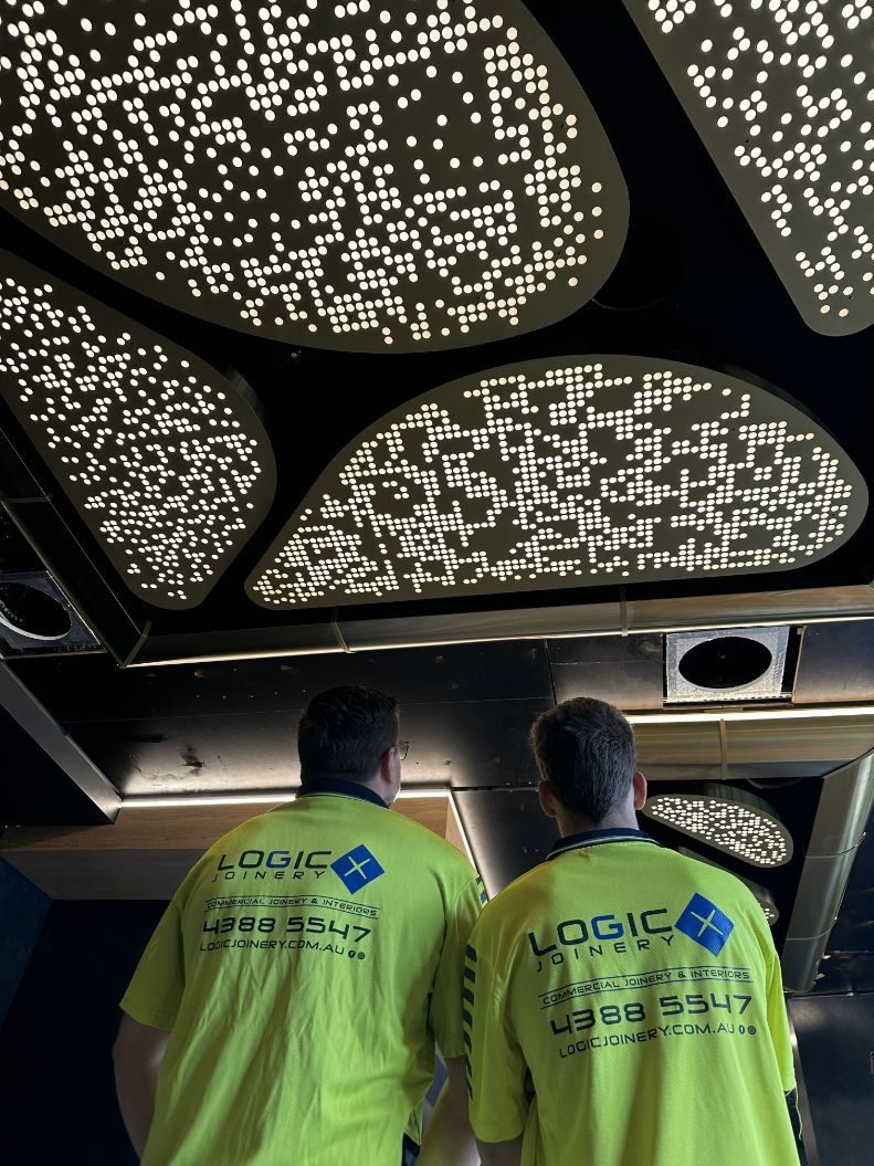 Two Men Wearing Yellow Logic Shirts Are Standing In Front Of A Ceiling — Logic Joinery In Fountaindale, NSW