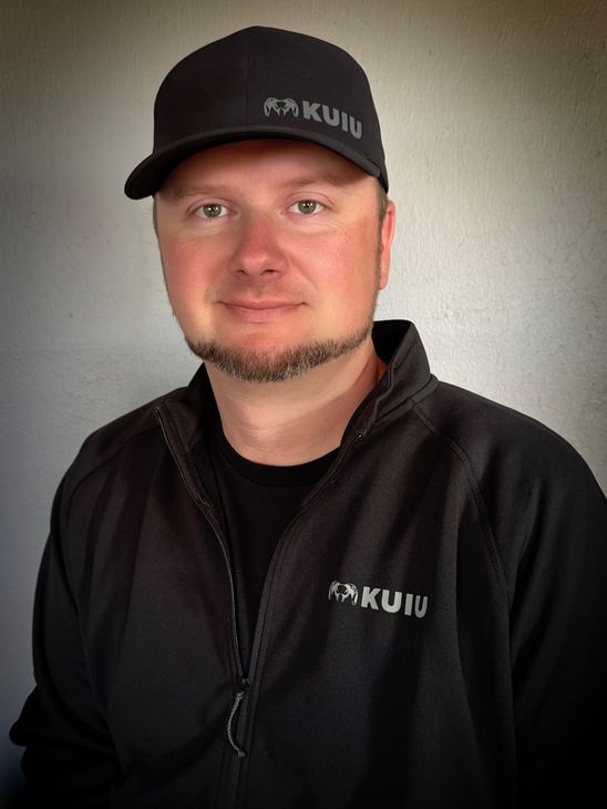 A woman is sitting at a desk with a laptop and a vase of flowers.