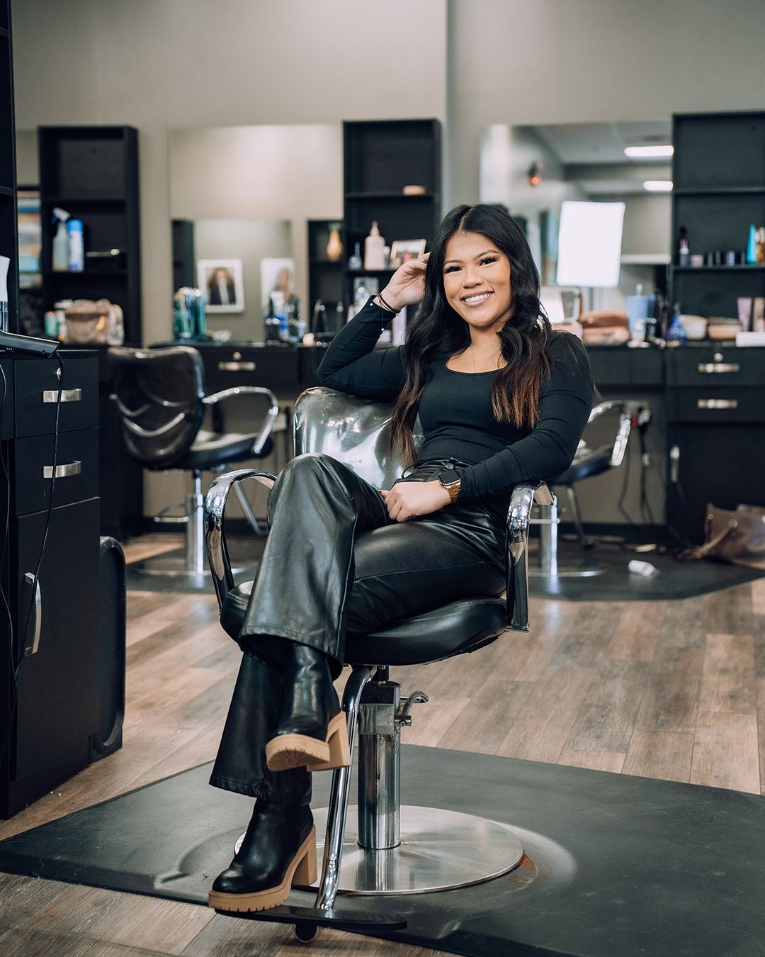 A woman is sitting in a chair in a hair salon.