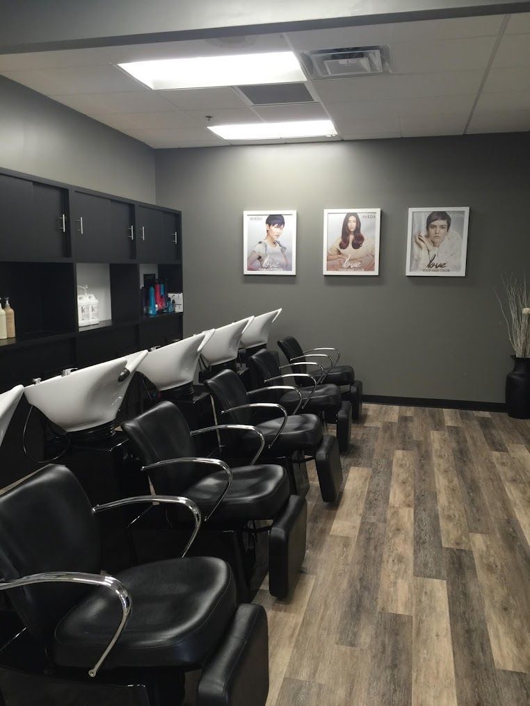 A row of hair wash chairs in a salon with pictures on the wall.