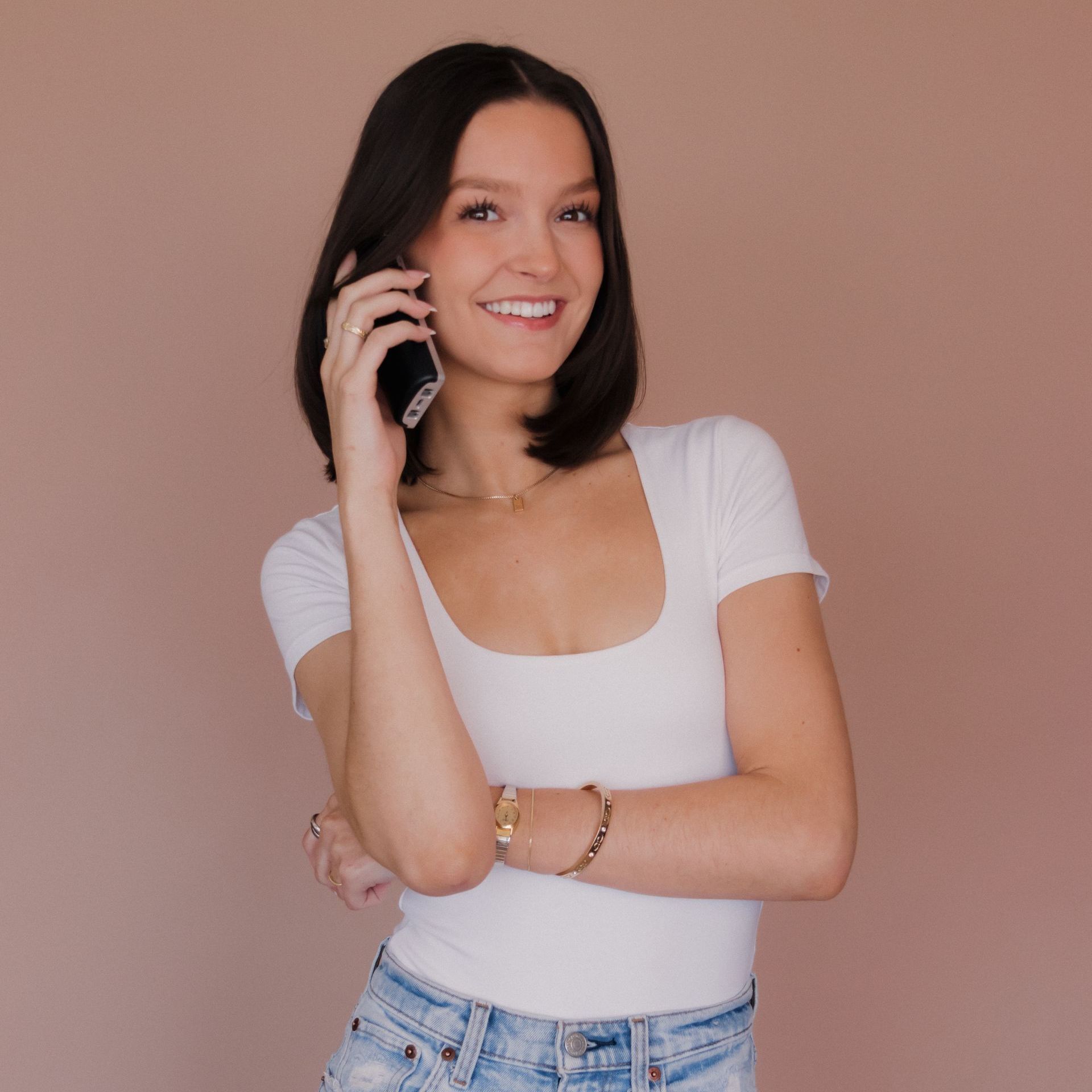 A woman is smiling while talking on a cell phone.