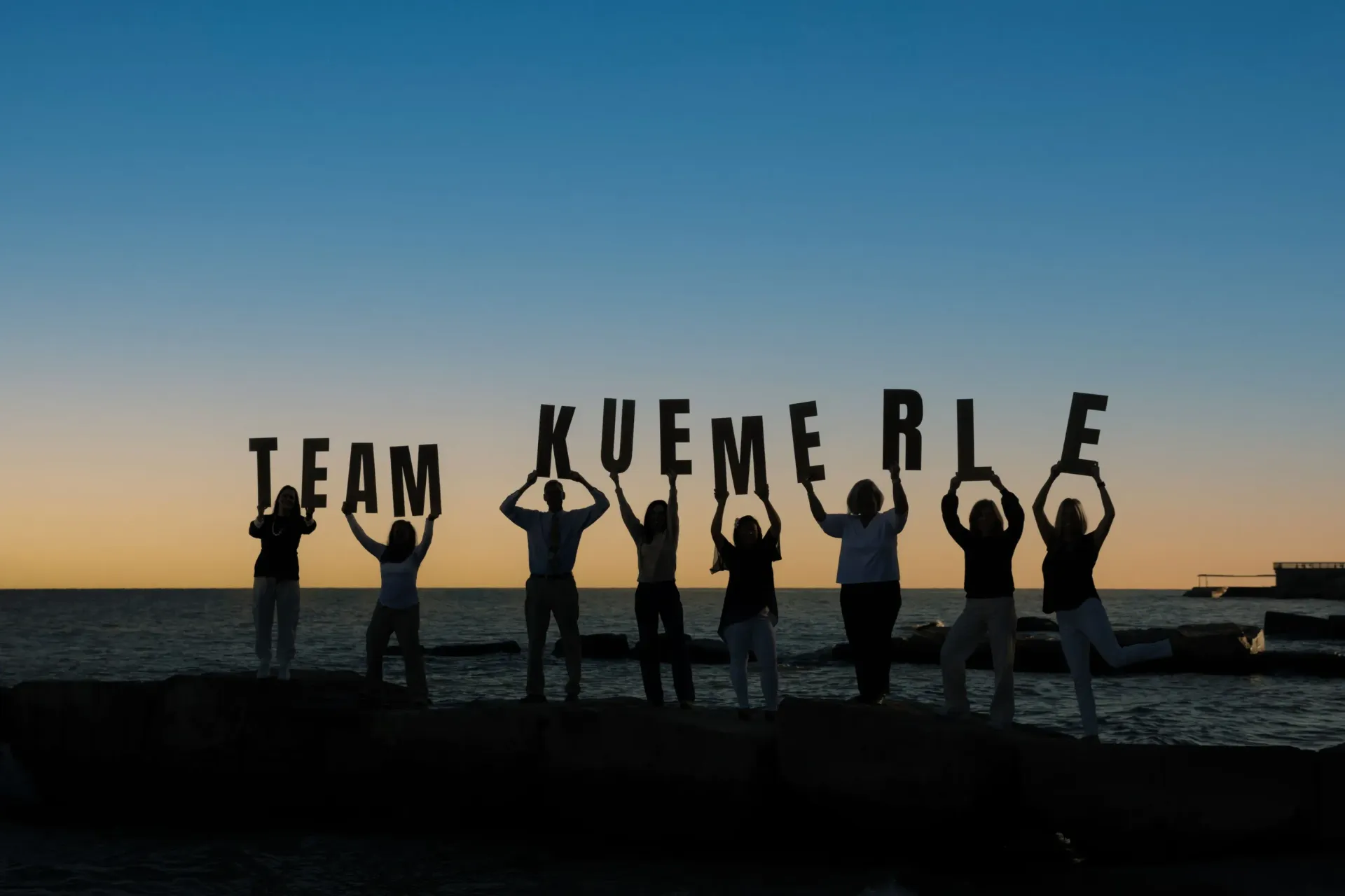 Silhouetted group holding letters spelling 