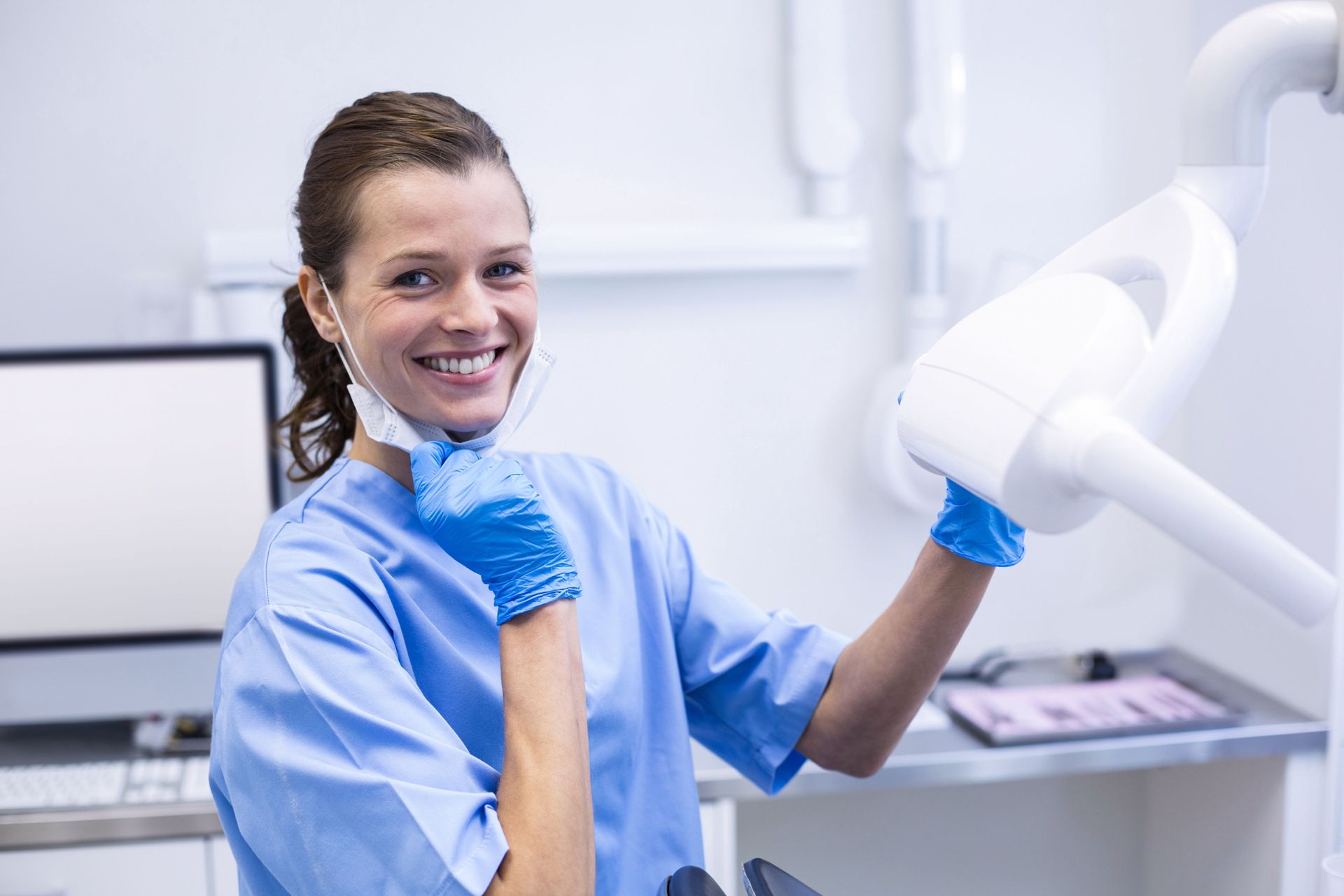 Smiling dental assistant adjusting light.