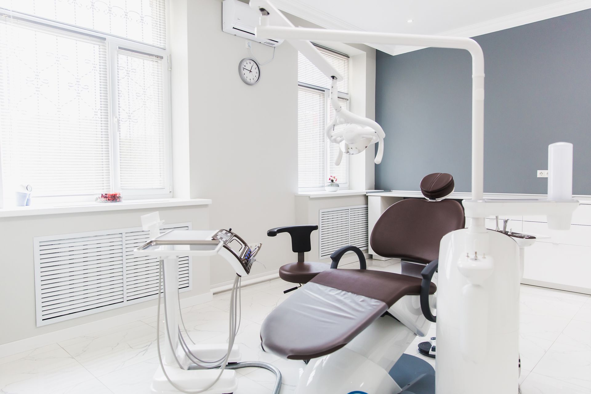 Dental operatory with a brown dental chair, white walls, and a window.