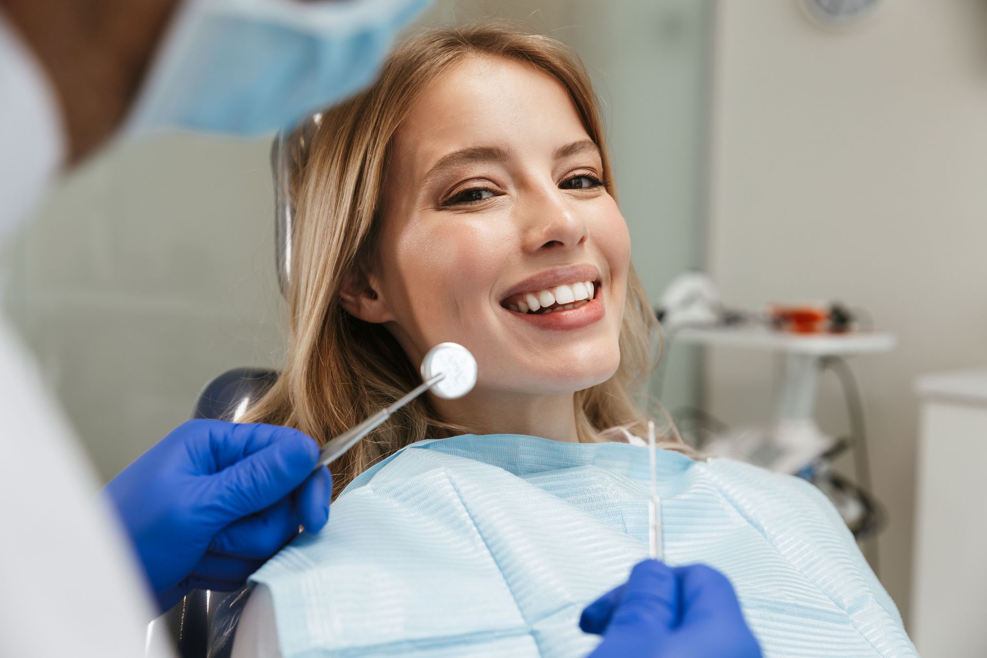 Dentist examining a patient in a dental chair using dental tools.