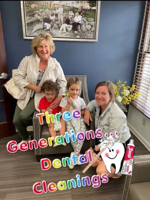 Two women and two children seated in a room, smiling. One child sits on a woman’s lap, the other is next to them. Artwork on wall.