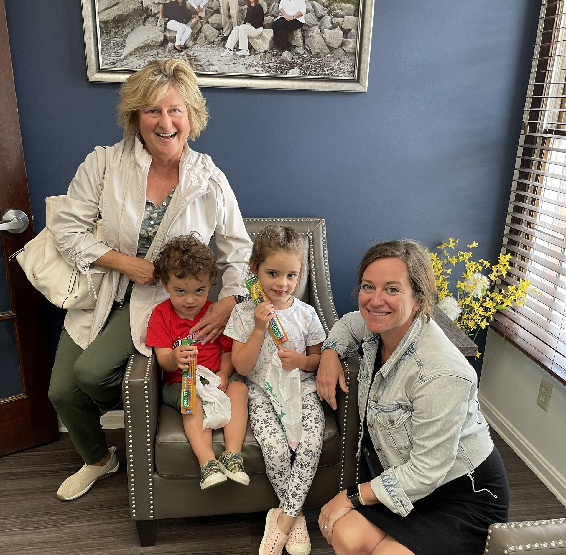 Two adults and two children pose indoors, smiling. One child holds candy.