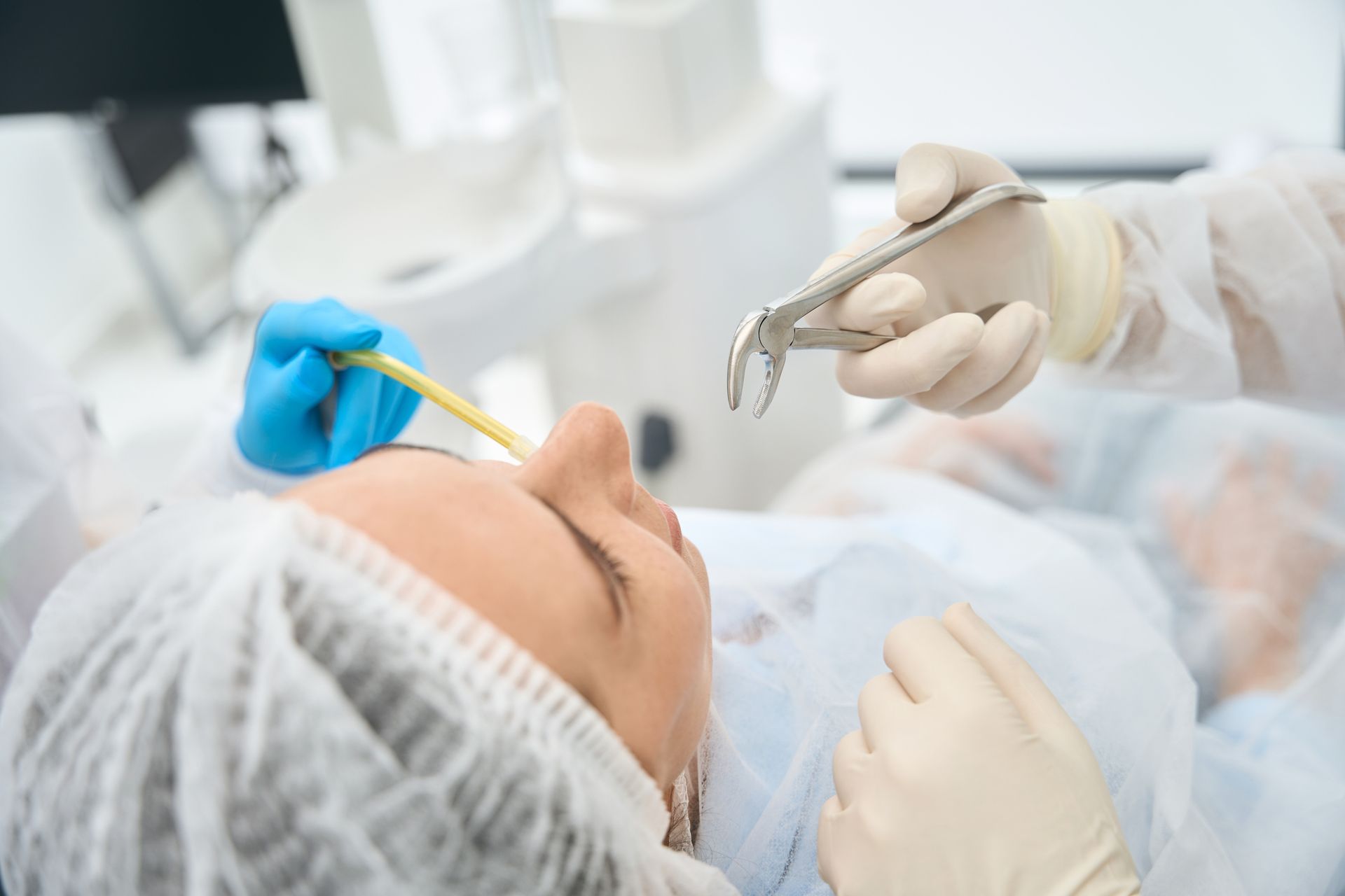 Patient in dental chair, doctor holding forceps, preparing for tooth extraction.