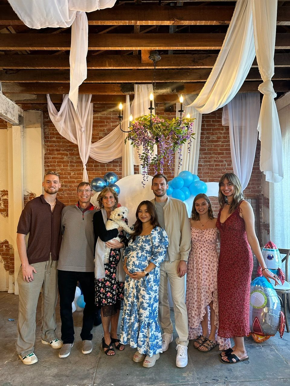 Santa Claus with elves in red and green costumes on a street with buildings.