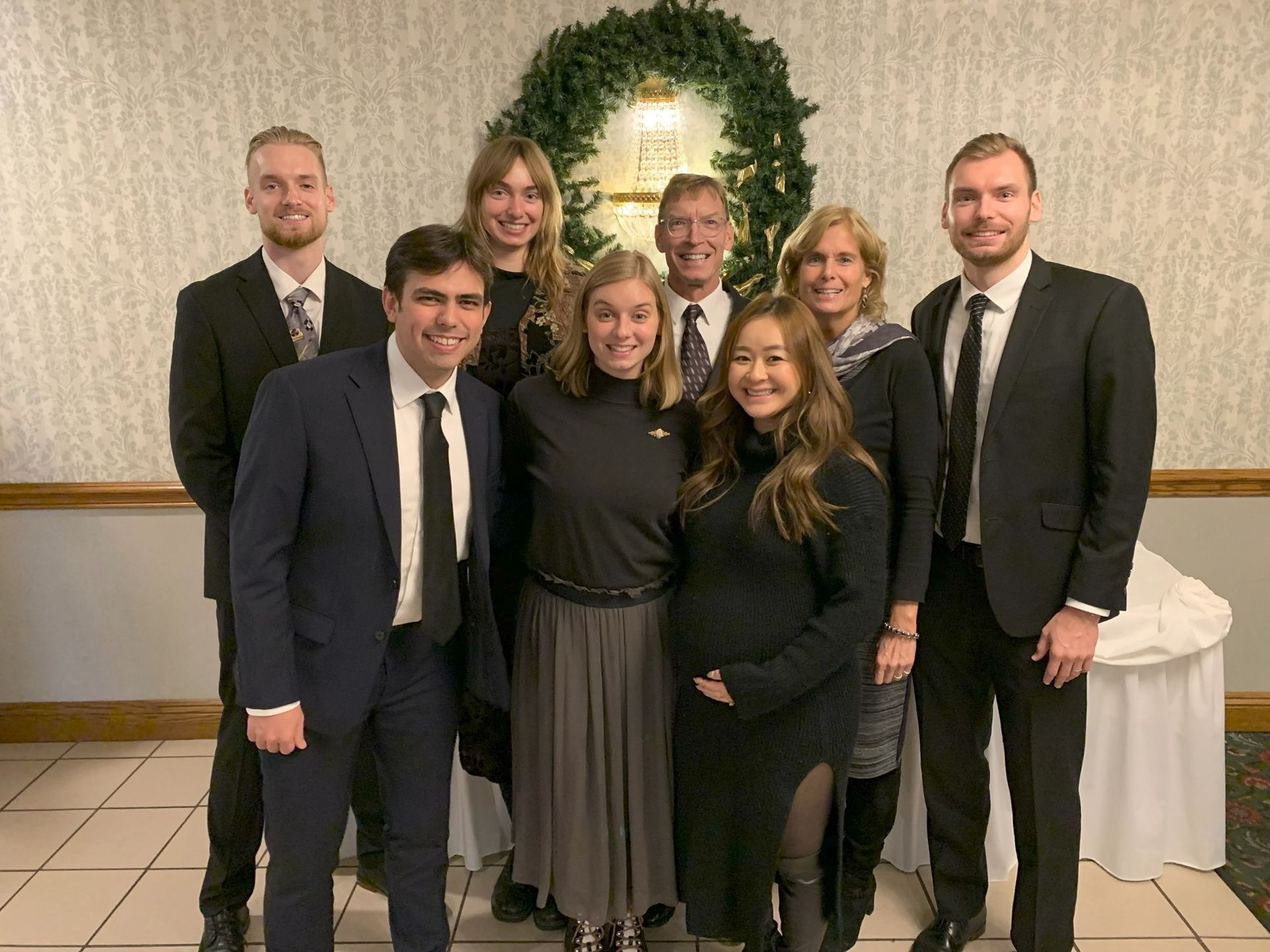 Santa Claus with elves in red and green costumes on a street with buildings.