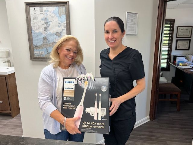 Child in dentist chair with dental professional in blue scrubs.