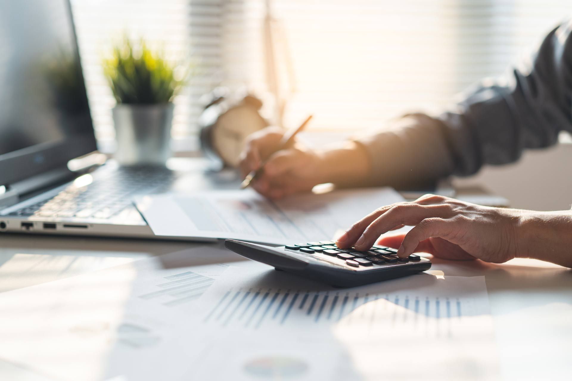 Close-up of a seasoned bookkeeper performing business tax preparation in an office.