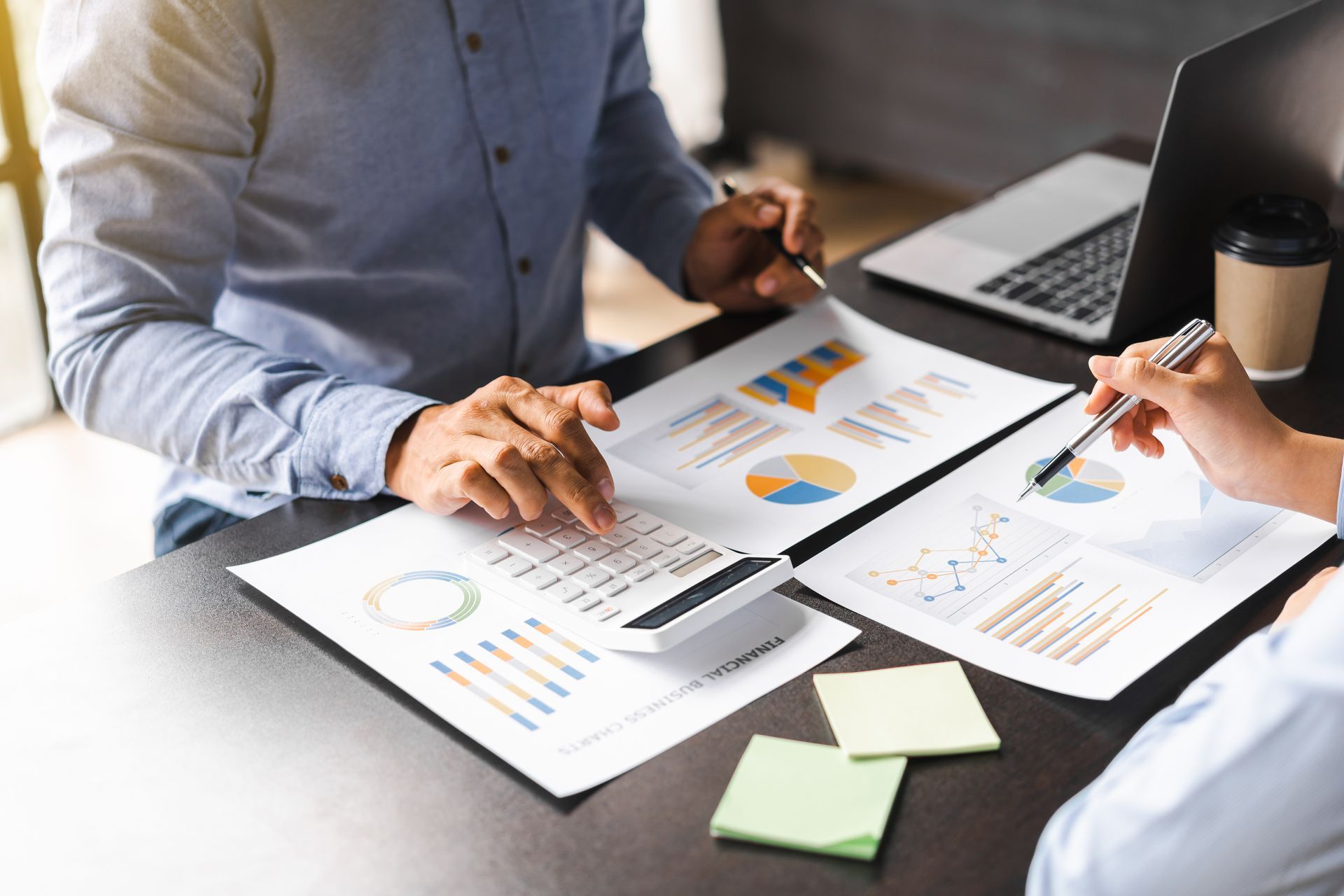 A team of financiers using a calculator to work on personal taxes.
