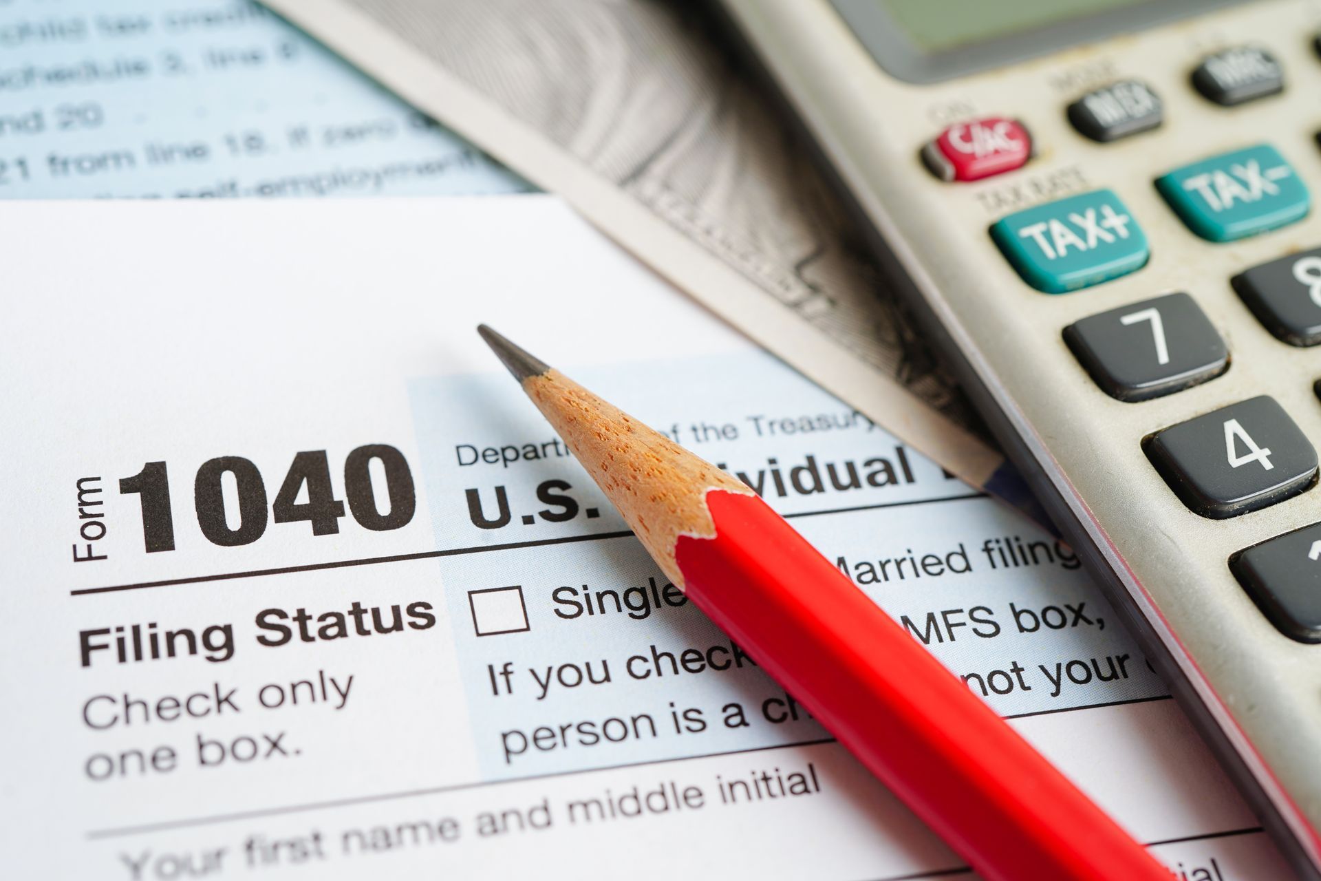 U.S. 1040 income tax form on desk beside calculator and pen.
